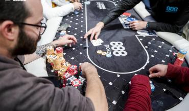 Players competing at an 888poker live table, with chip stacks and cards visible